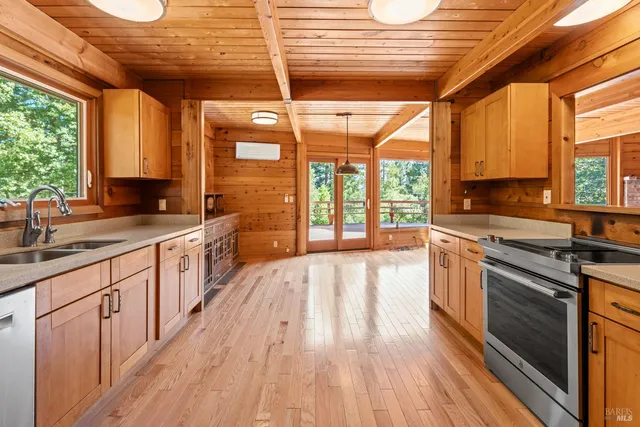 a large kitchen with a large window a sink dishwasher and wooden floor