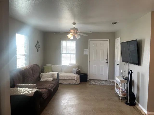 a living room with furniture a flat screen tv and a window