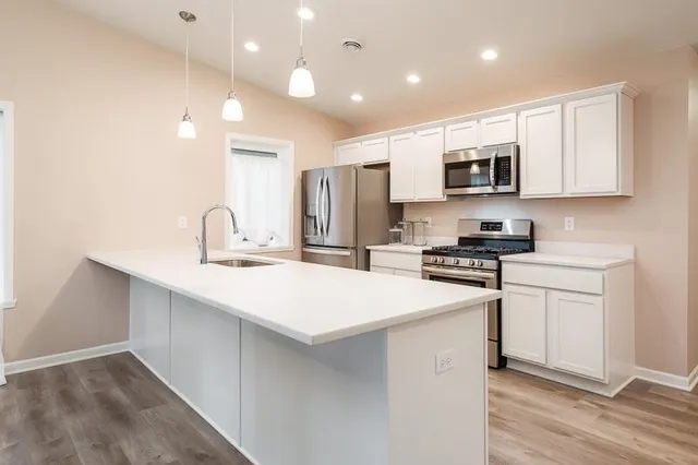 a kitchen with stainless steel appliances a sink a stove a microwave a refrigerator a counter top space and cabinets