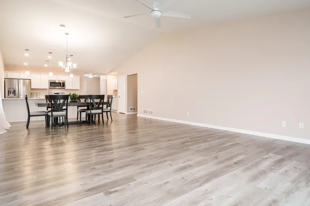 an open kitchen with wooden floor and dining table