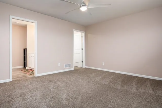 an empty room with a window and ceiling fan