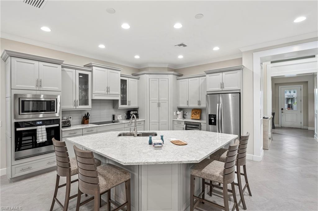 8795 Calypso Court Naples, FL 34113 - Photo 10 of 49 a kitchen with stainless steel appliances kitchen island granite countertop a dining table and chairs