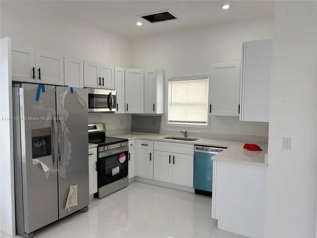a kitchen with a sink cabinets stainless steel appliances and a window