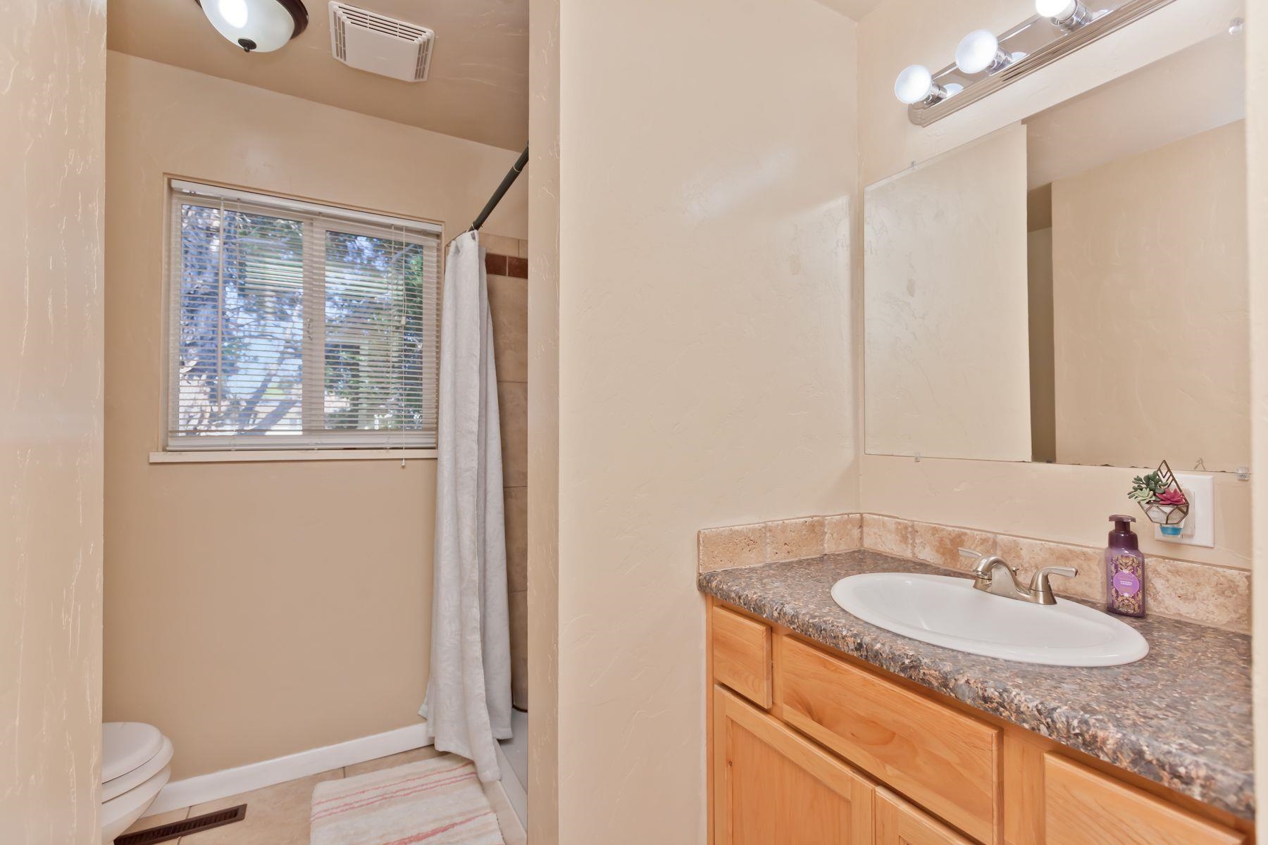 498 Sheldon Road Grand Junction, CO 81504 - Photo 31 of 42 a bathroom with a granite countertop sink a mirror and a shower