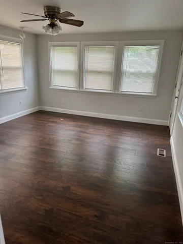 an empty room with wooden floor cabinet and windows