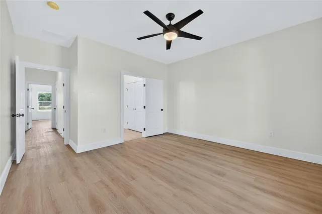an empty room with wooden floor and a ceiling fan