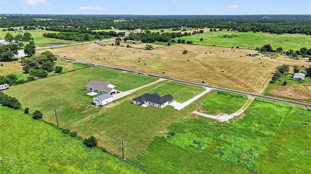 an aerial view of residential houses with outdoor space and trees