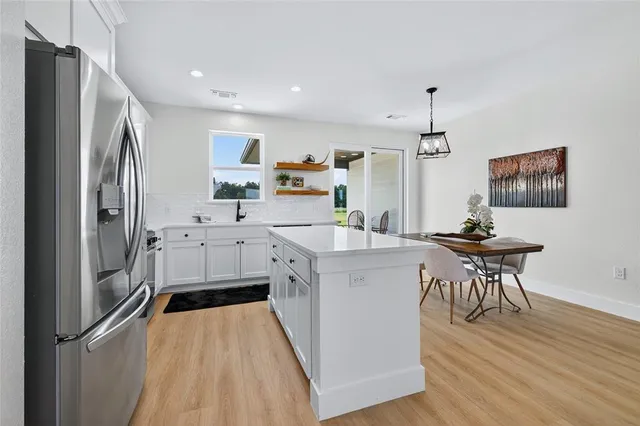 a kitchen with stainless steel appliances a refrigerator a stove a sink dishwasher and a dining table with wooden floor