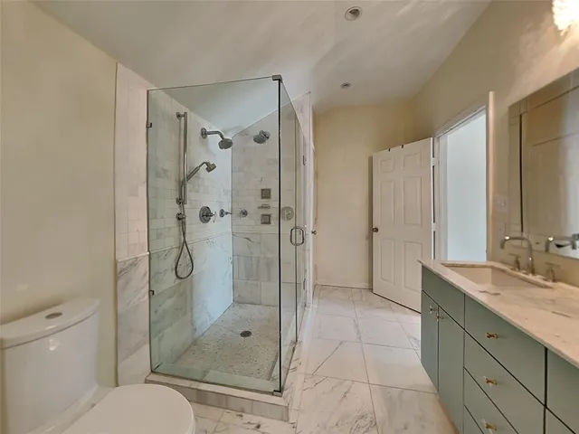 a bathroom with a shower sink mirror and toilet