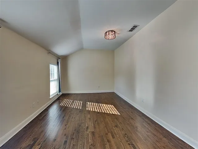 a view of an empty room with wooden floor and window