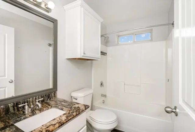 a bathroom with a granite countertop sink toilet and shower
