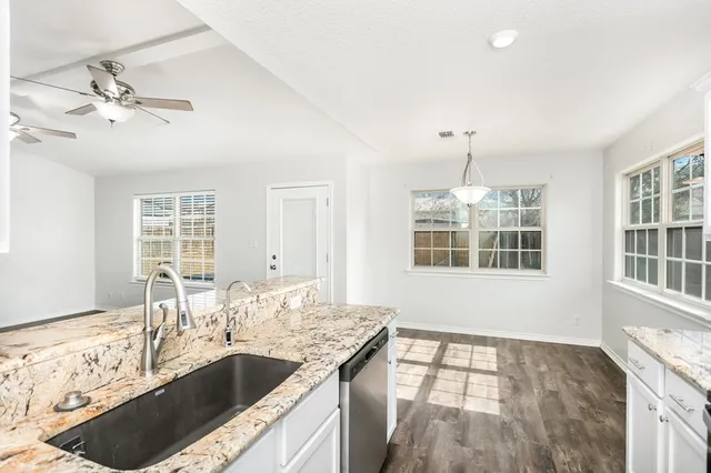 a kitchen with granite countertop a sink stove and cabinets