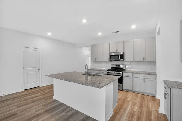 a kitchen with stainless steel appliances granite countertop a sink stove and refrigerator