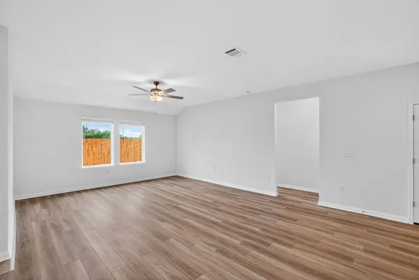 a view of an empty room with wooden floor and a window