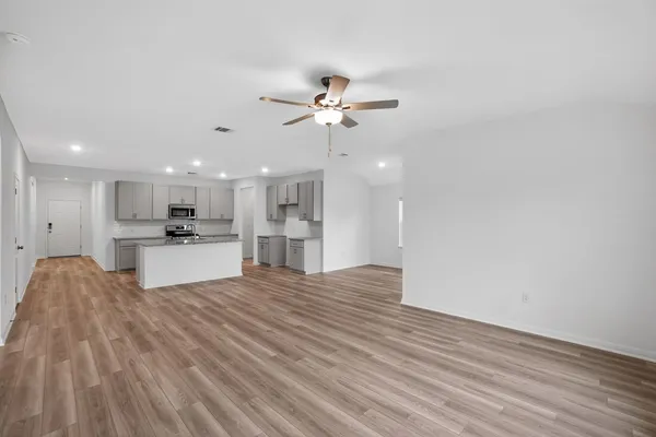 a view of kitchen with kitchen island wooden floor center island and stainless steel appliances