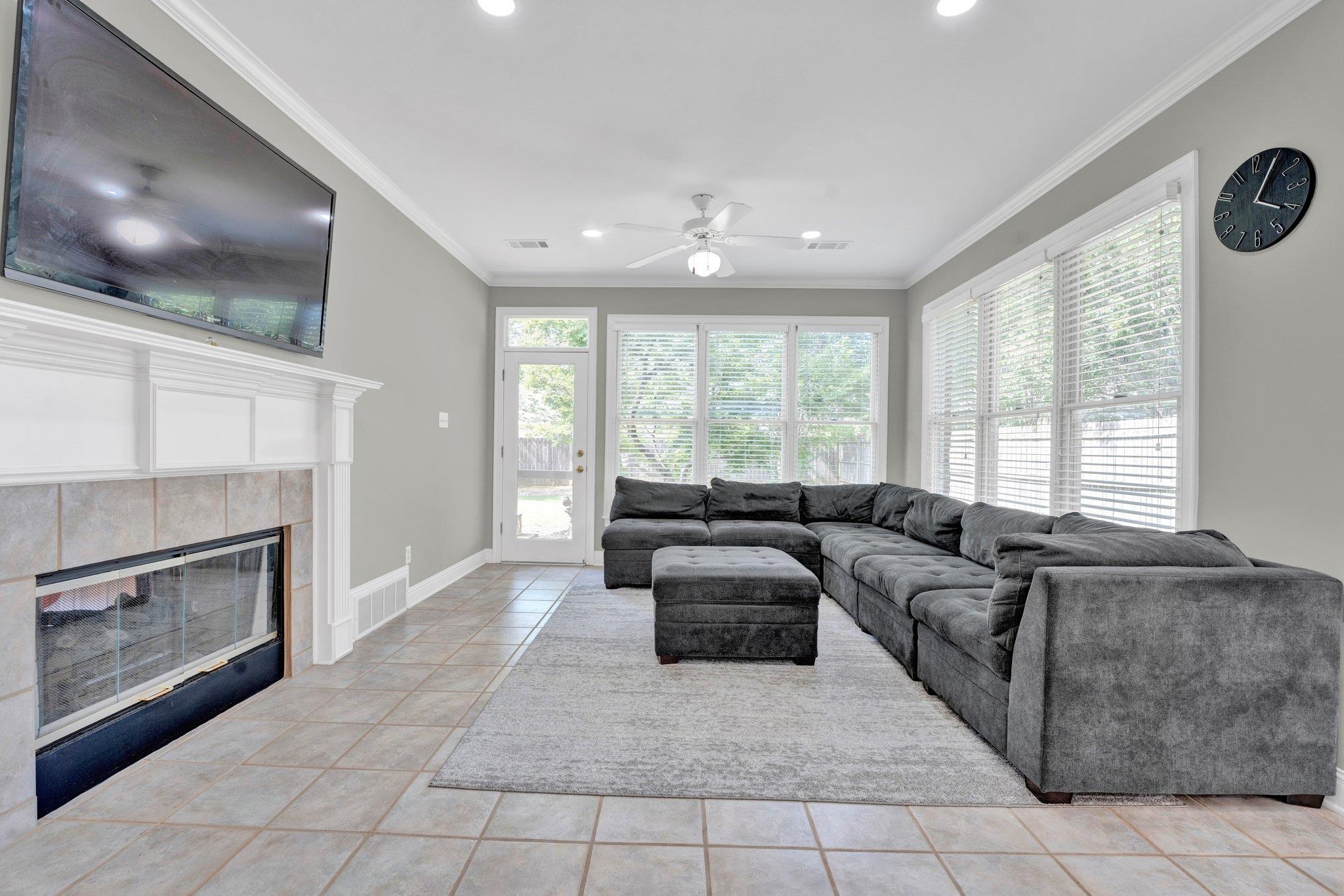 1331 Riding Brook Drive Collierville, TN 38017 - Photo 12 of 39 Tiled living room featuring a tiled fireplace, ceiling fan, and ornamental molding