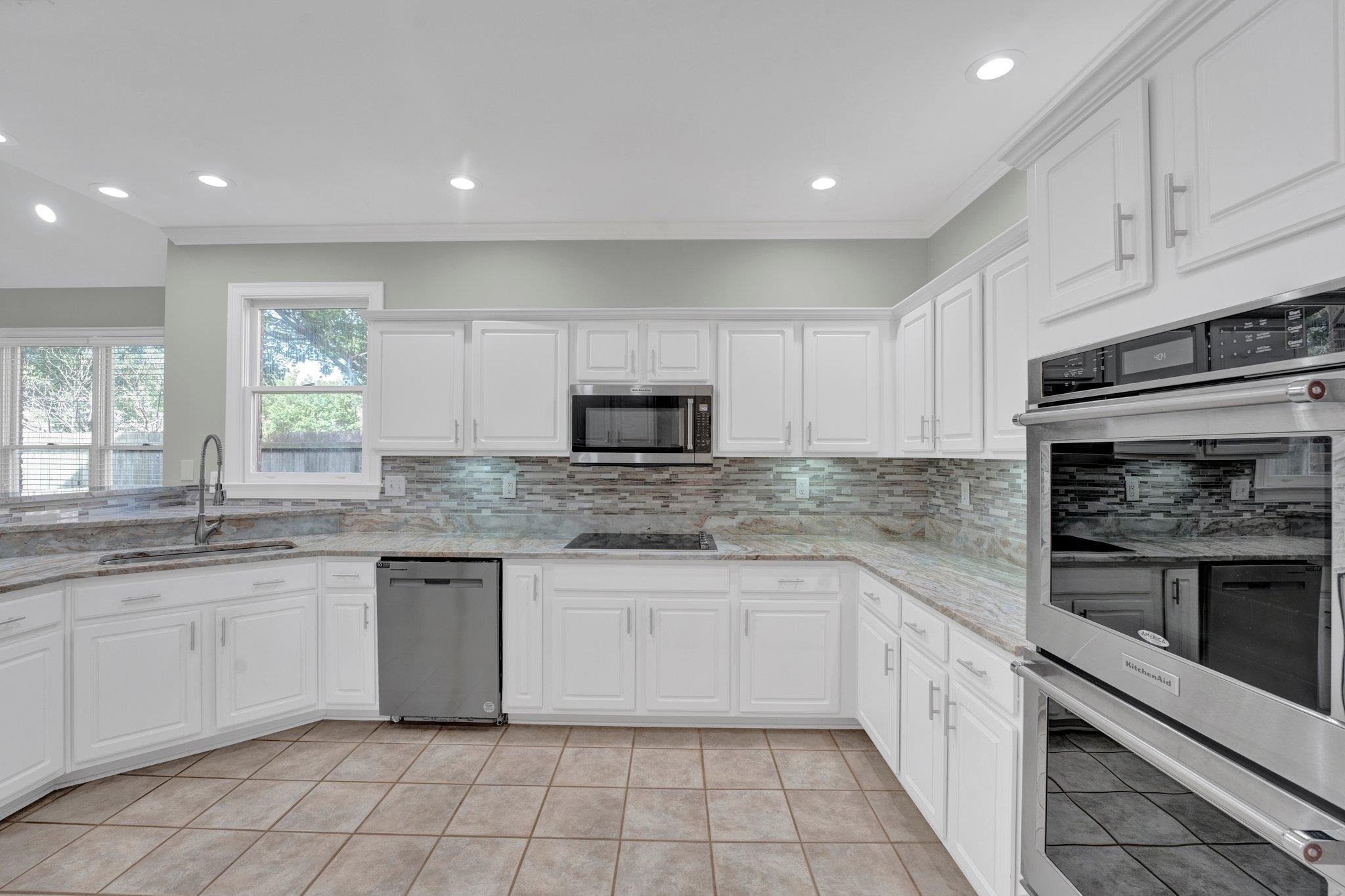 1331 Riding Brook Drive Collierville, TN 38017 - Photo 15 of 39 Kitchen with appliances with stainless steel finishes, white cabinetry, decorative backsplash, and sink