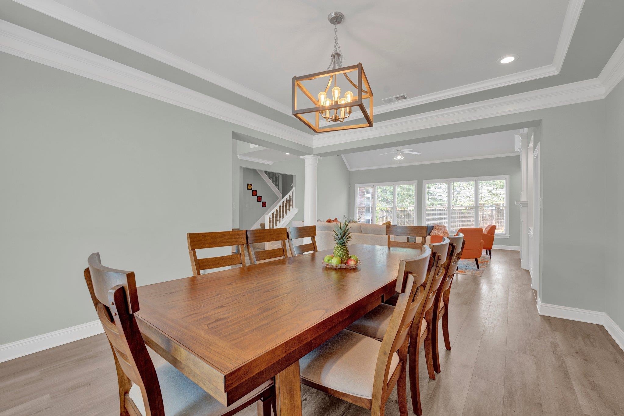 1331 Riding Brook Drive Collierville, TN 38017 - Photo 8 of 39 Dining room with ceiling fan with notable chandelier, ornamental molding, light wood-type flooring, and a tray ceiling