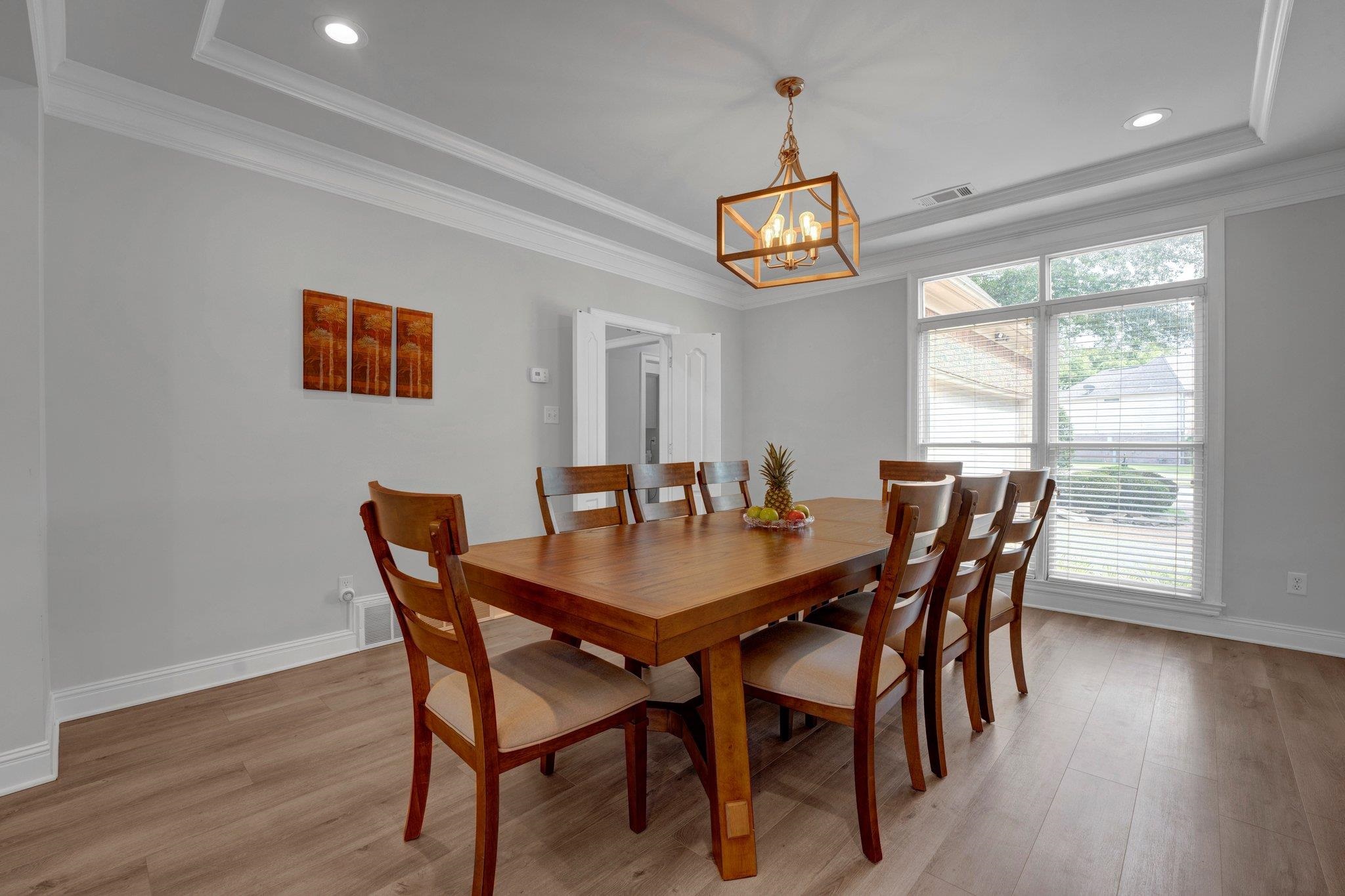 1331 Riding Brook Drive Collierville, TN 38017 - Photo 9 of 39 Dining area with a notable chandelier, light hardwood / wood-style flooring, crown molding, and a tray ceiling