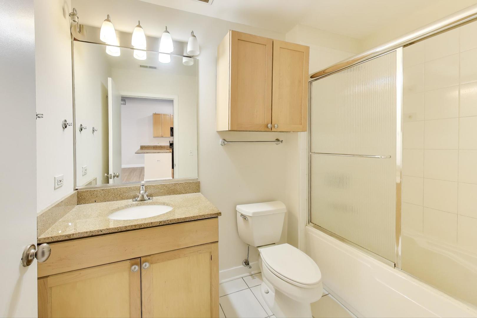 910 West Madison Street, Unit 409 Chicago, IL 60607 - Photo 9 of 14 a bathroom with a granite countertop sink toilet and shower