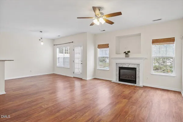 a view of an empty room with a window and wooden floor