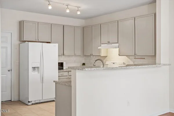 a close view of a kitchen with refrigerator and white cabinets