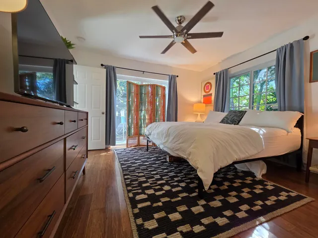 a living room with large bed and a flat tv screen on dresser