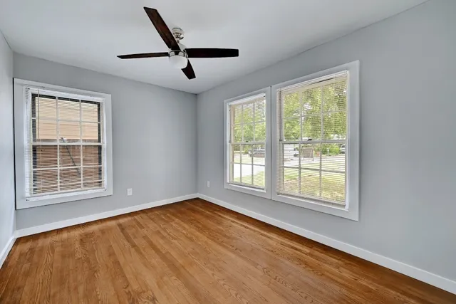 a view of an empty room with a window and wooden floor