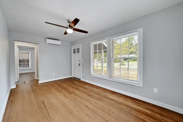 a view of empty room with wooden floor and fan