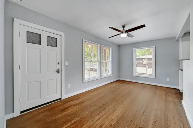 a view of empty room with wooden floor and fan