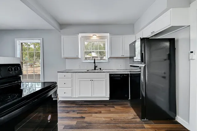 a kitchen with granite countertop a sink cabinets and stainless steel appliances