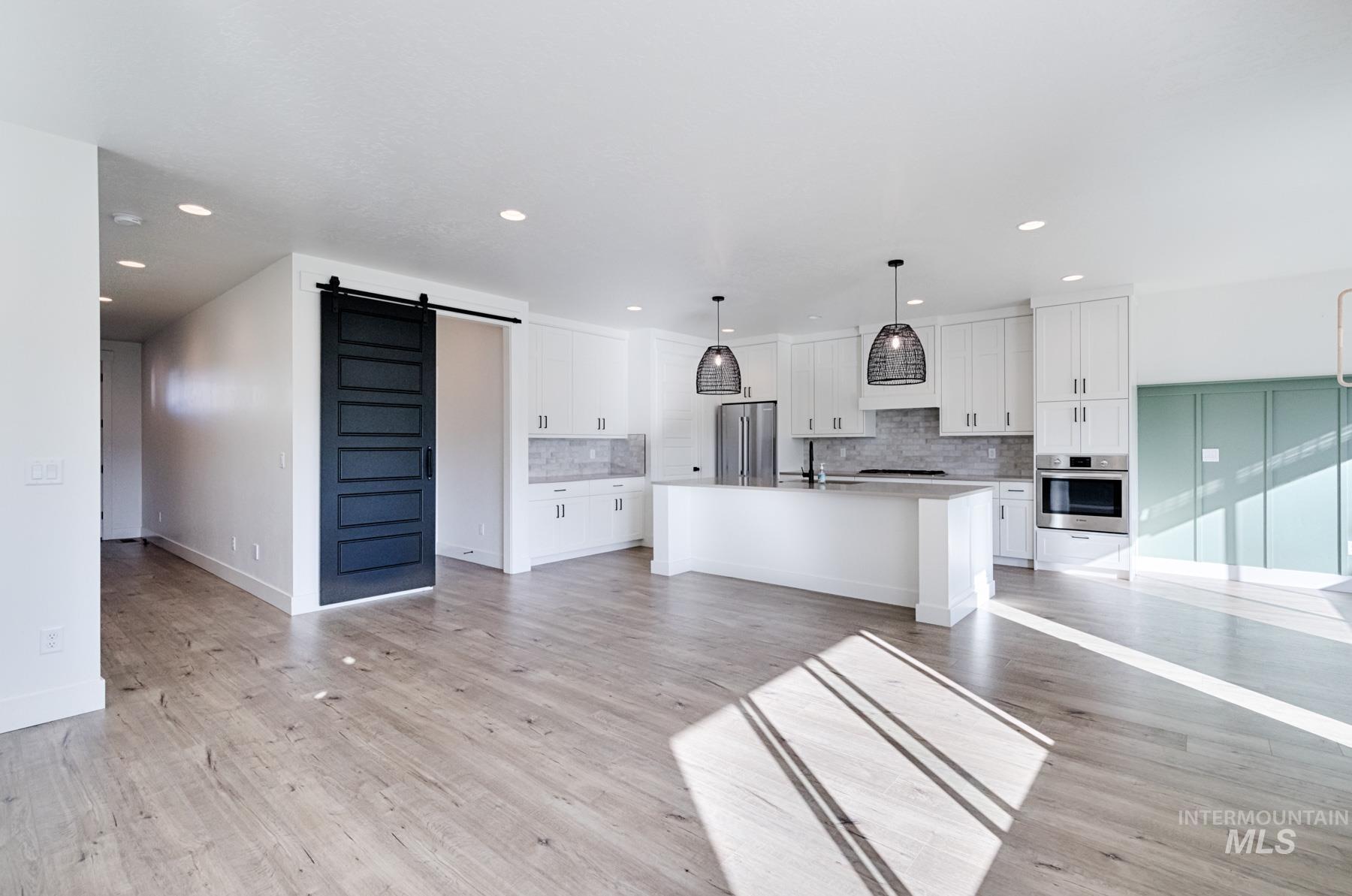 6216 South Wayland Way Meridian, ID 83642 - Photo 11 of 38 Open-concept living space featuring wood-finish flooring, recessed lighting, and a modern kitchen