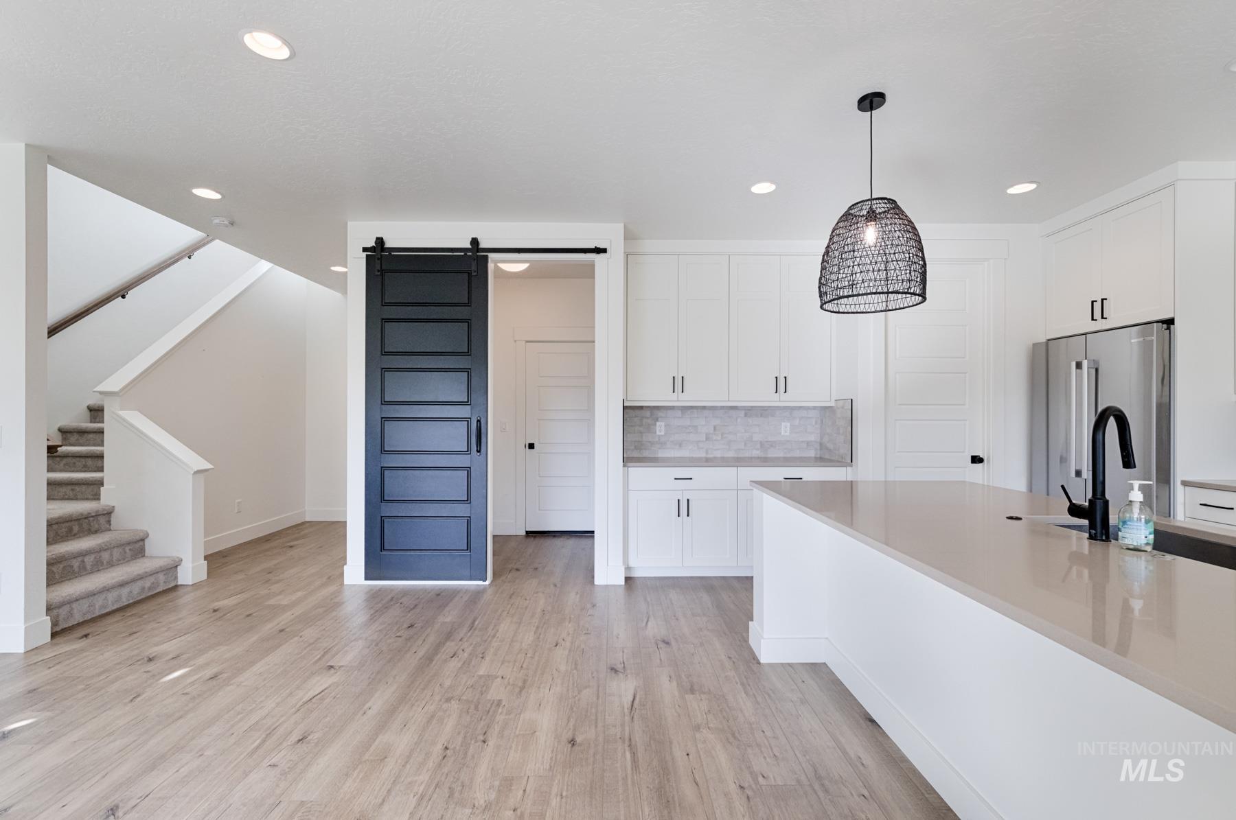 6216 South Wayland Way Meridian, ID 83642 - Photo 13 of 38 Open-concept living space with wood-finish flooring, a contemporary kitchen, and a carpeted staircase