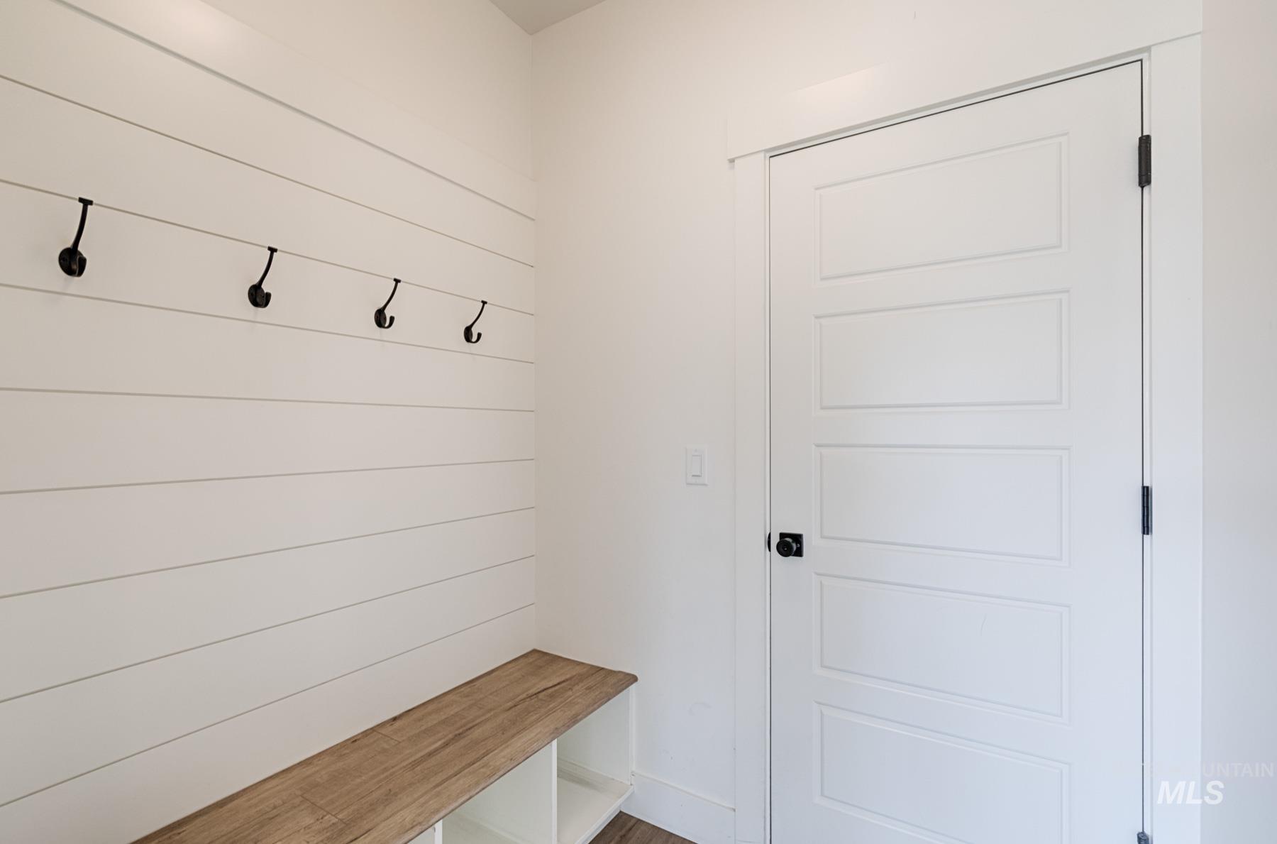 6216 South Wayland Way Meridian, ID 83642 - Photo 18 of 38 Entryway featuring shiplap wall paneling, a built-in wood-finish bench with open storage, and five matte black coat hooks