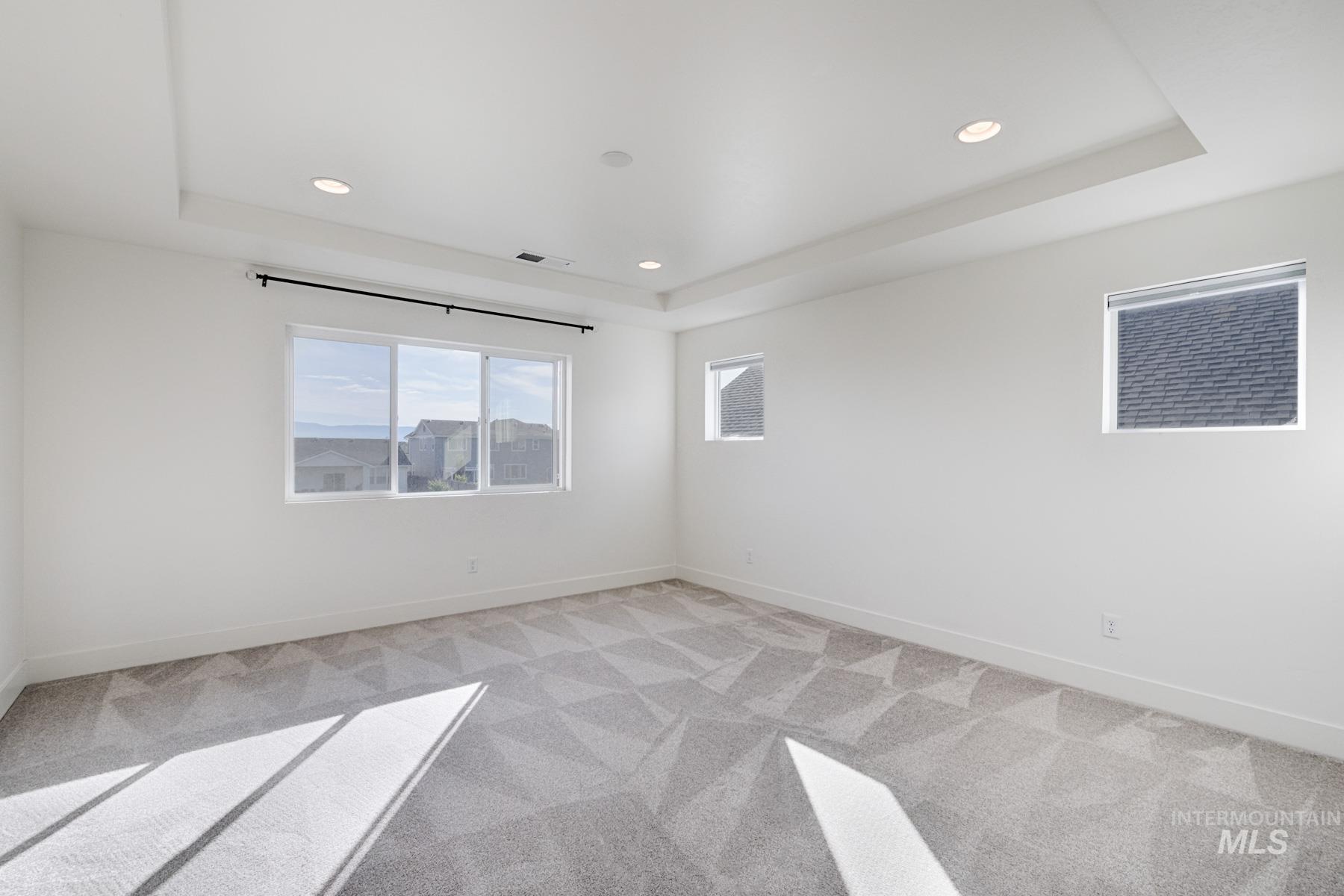 6216 South Wayland Way Meridian, ID 83642 - Photo 19 of 38 Expansive room featuring a tray ceiling with recessed lighting, large windows, and geometric patterned carpet