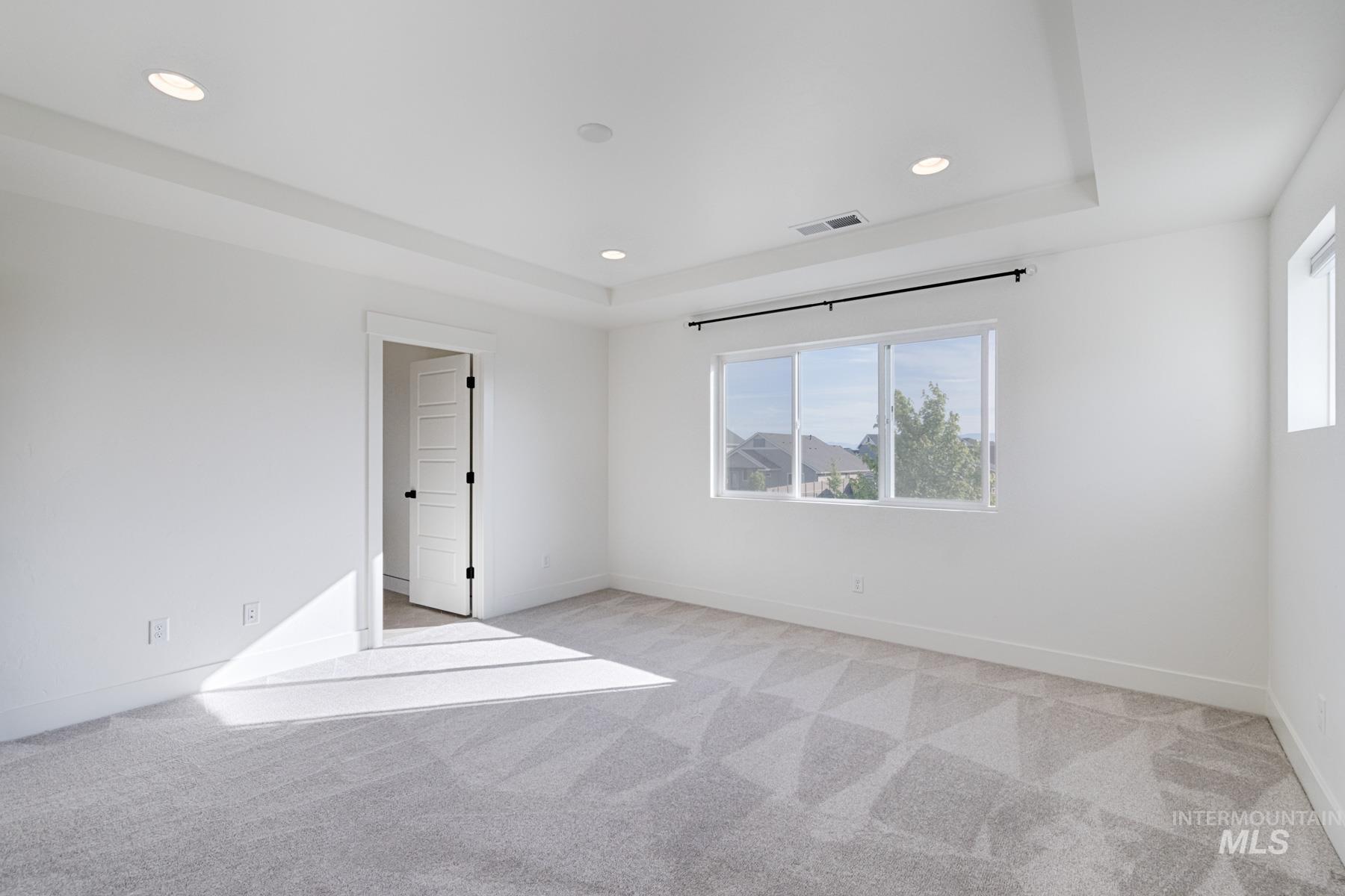 6216 South Wayland Way Meridian, ID 83642 - Photo 20 of 38 Spacious interior room featuring a tray ceiling with recessed lighting, light gray patterned carpeting, and white walls