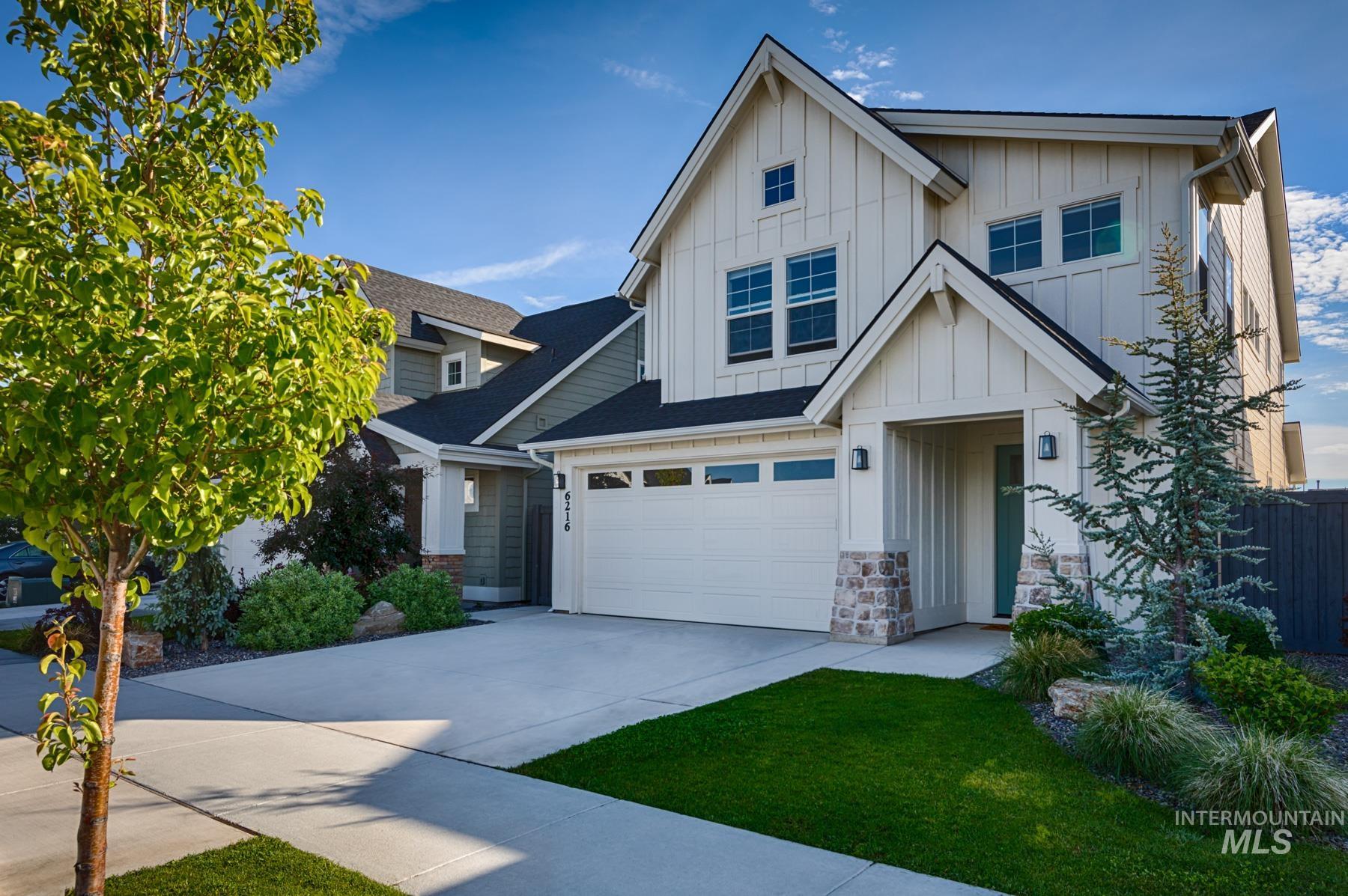 6216 South Wayland Way Meridian, ID 83642 - Photo 2 of 38 Modern farmhouse exterior featuring board and batten siding, stone accents, a two-car garage, manicured lawn, and mature landscaping