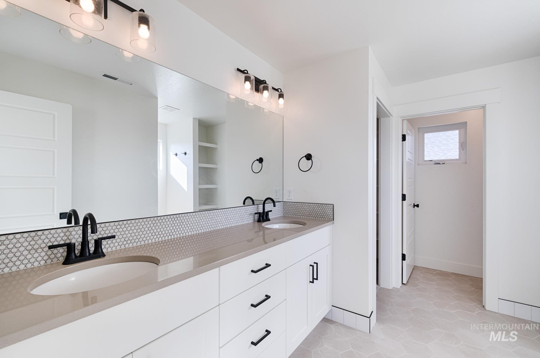 6216 South Wayland Way Meridian, ID 83642 - Photo 21 of 38 Double vanity featuring undermount sinks, stone countertops, matte black faucets, and a full-width mirror