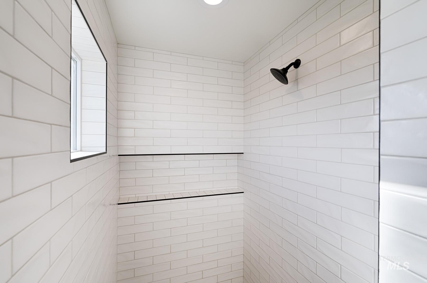 6216 South Wayland Way Meridian, ID 83642 - Photo 23 of 38 Shower enclosure featuring white subway tile, a matte black showerhead, built-in shelving, recessed lighting, and a frosted window