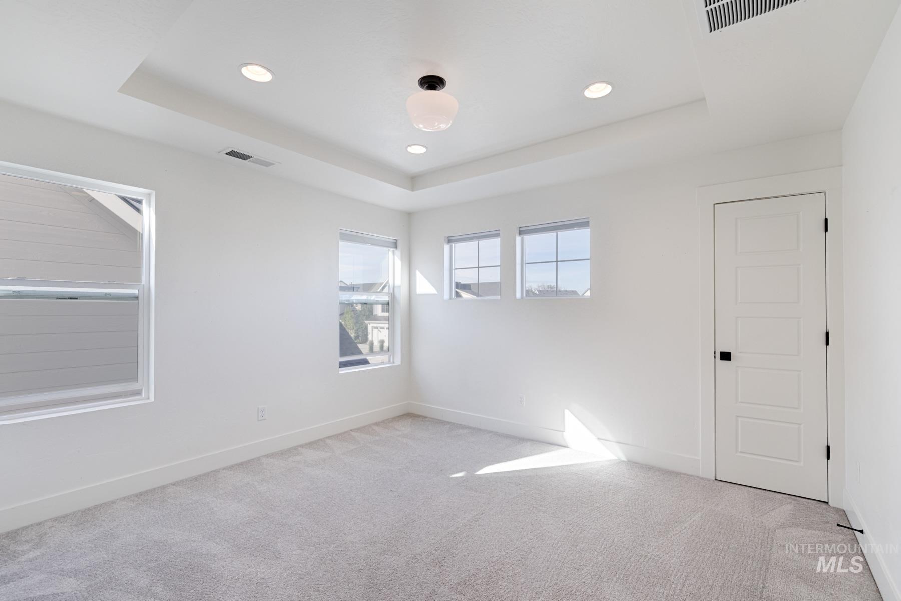 6216 South Wayland Way Meridian, ID 83642 - Photo 25 of 38 Bright interior space featuring light gray carpeting, crisp white walls, multiple windows, a tray ceiling, and recessed lighting