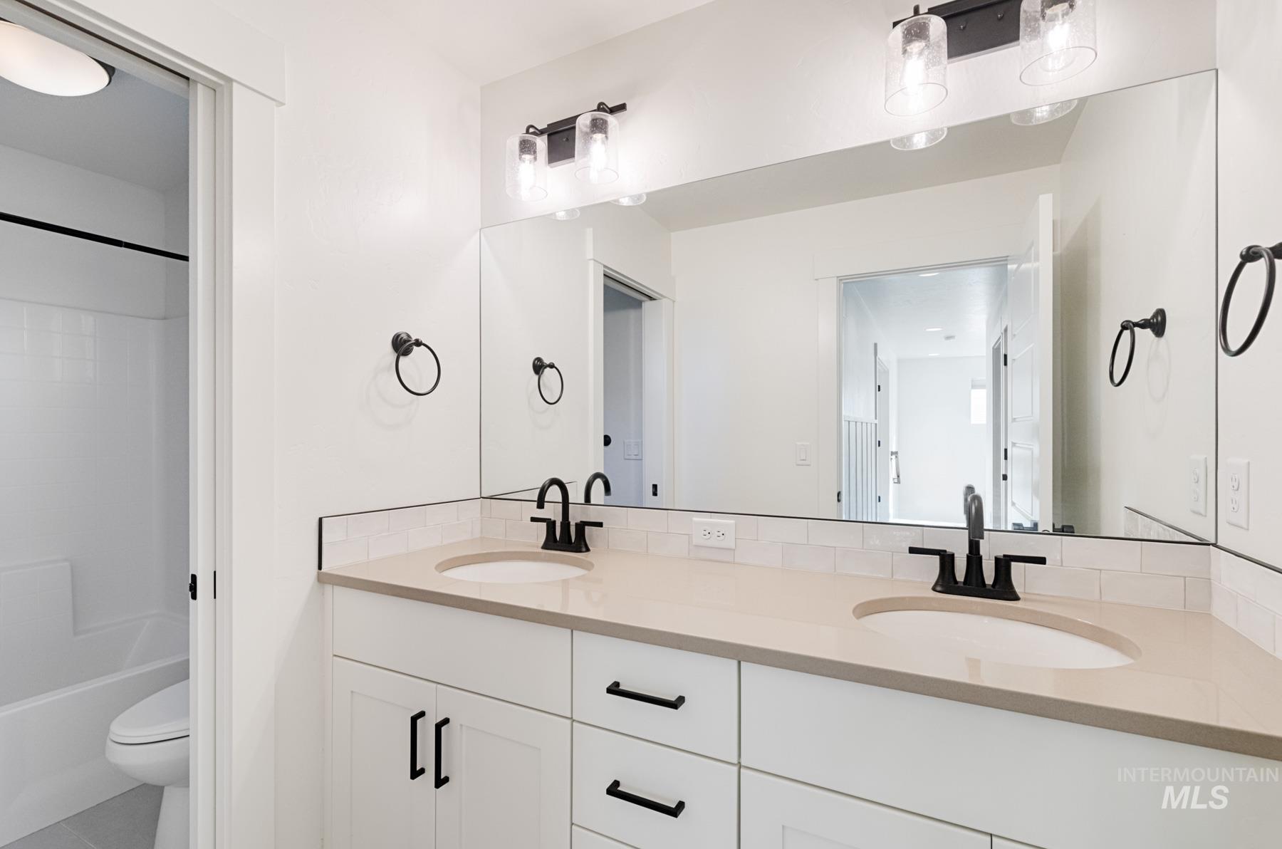 6216 South Wayland Way Meridian, ID 83642 - Photo 28 of 38 Bathroom featuring a dual-sink vanity with light-colored countertops, white cabinetry, and matte black fixtures