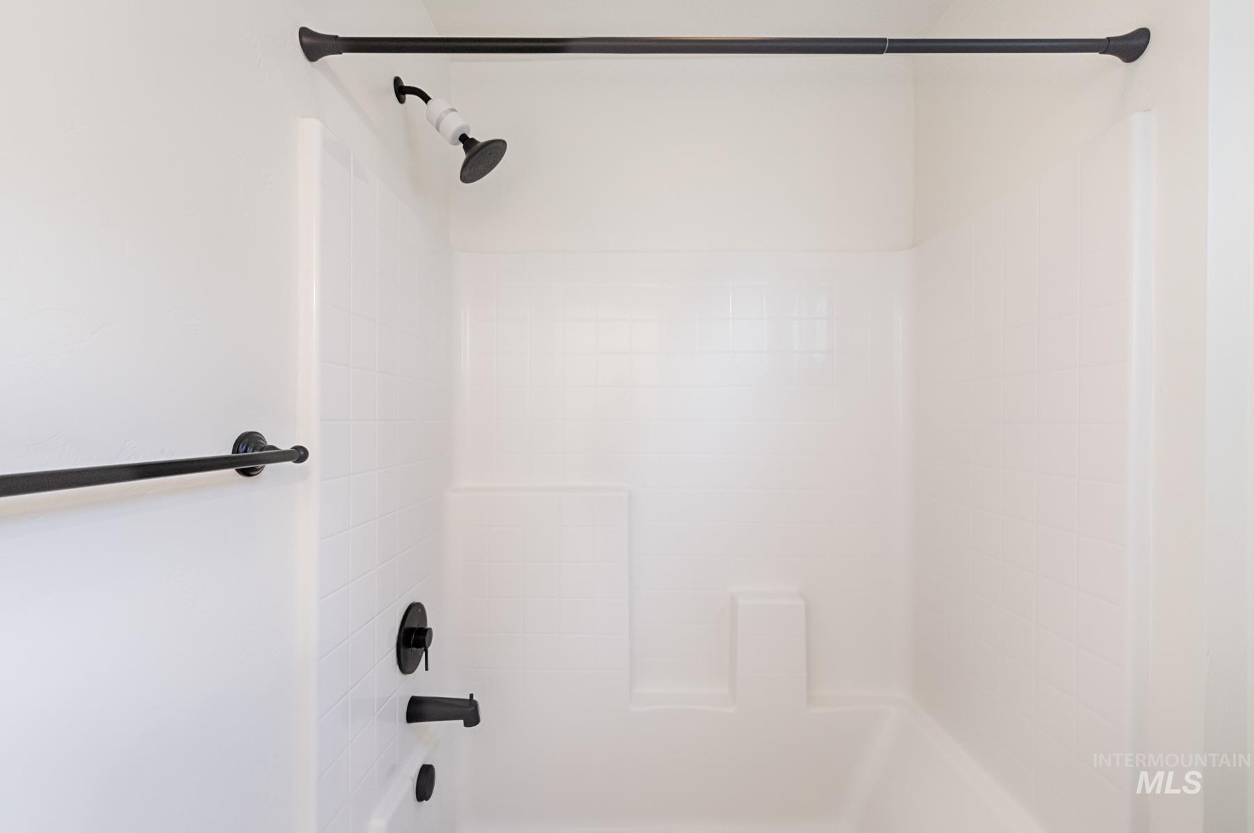 6216 South Wayland Way Meridian, ID 83642 - Photo 29 of 38 Bathtub and shower combination featuring a matte black shower head, faucet, and bath spout, complemented by a matte black shower rod and towel bar