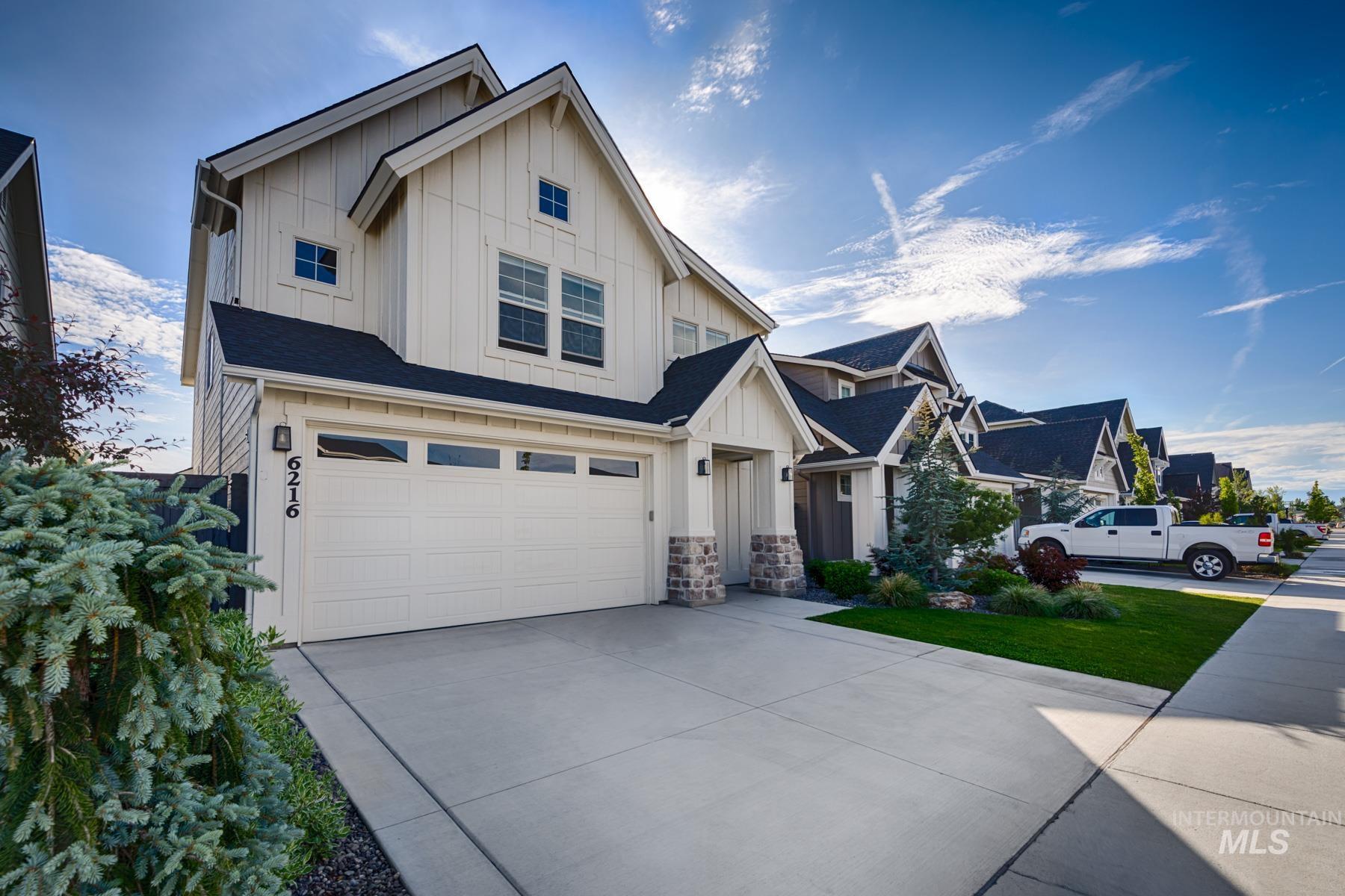 6216 South Wayland Way Meridian, ID 83642 - Photo 3 of 38 Modern farmhouse exterior featuring vertical white siding, dark shingle roofing, and stone accents