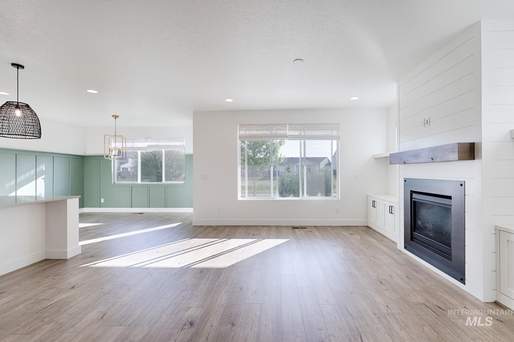 6216 South Wayland Way Meridian, ID 83642 - Photo 8 of 38 Spacious living area featuring wood-finish flooring, a contemporary fireplace with a wood mantle, and shiplap accent wall