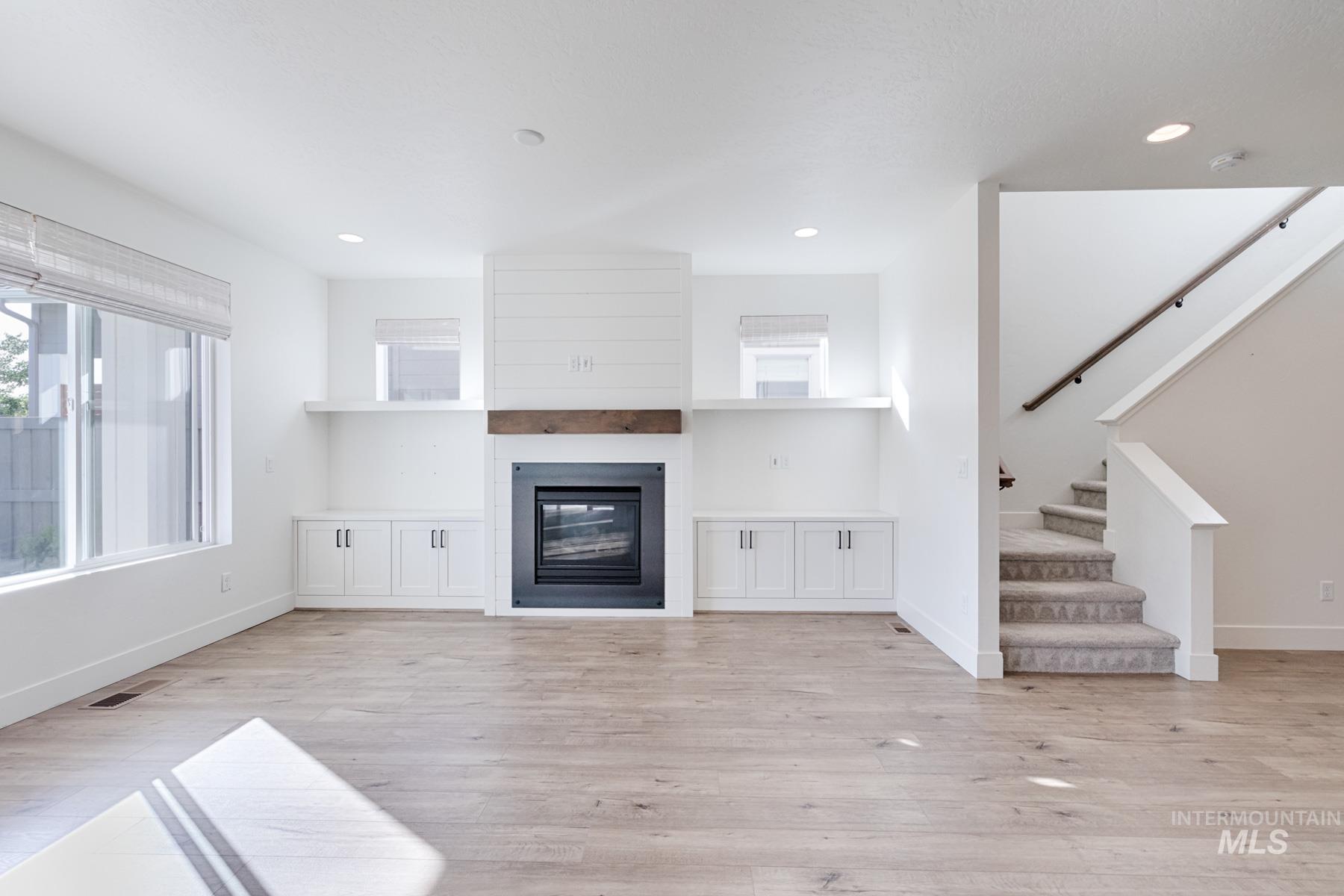 6216 South Wayland Way Meridian, ID 83642 - Photo 9 of 38 Living area featuring wood-finish flooring, a fireplace with a dark metal surround, a wood mantel, and shiplap detailing
