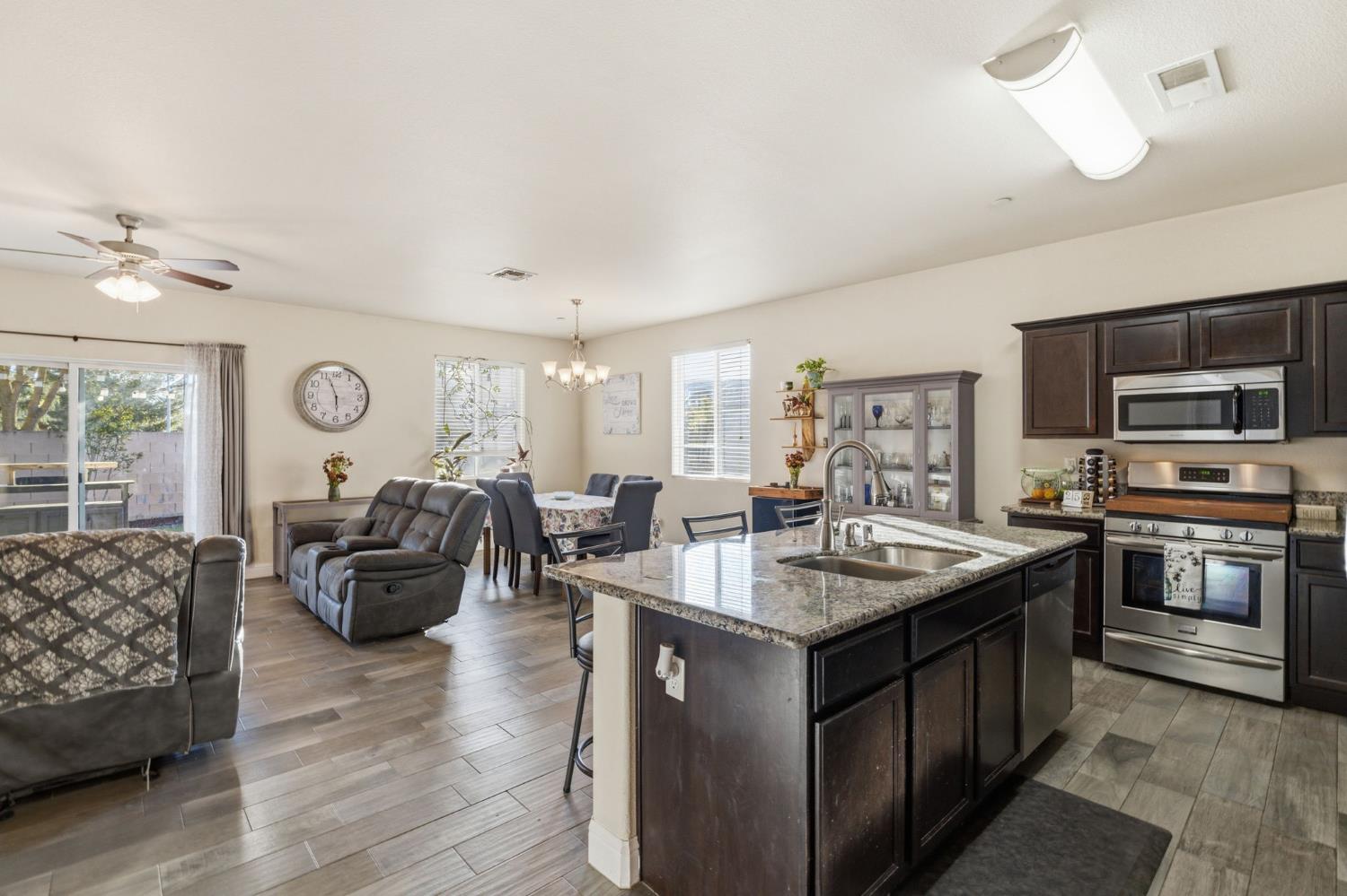15717 West Botelho Avenue Kerman, CA 93630 - Photo 26 of 43 a very nice looking living room with stainless steel appliances granite countertop furniture a fireplace and a ceiling fan
