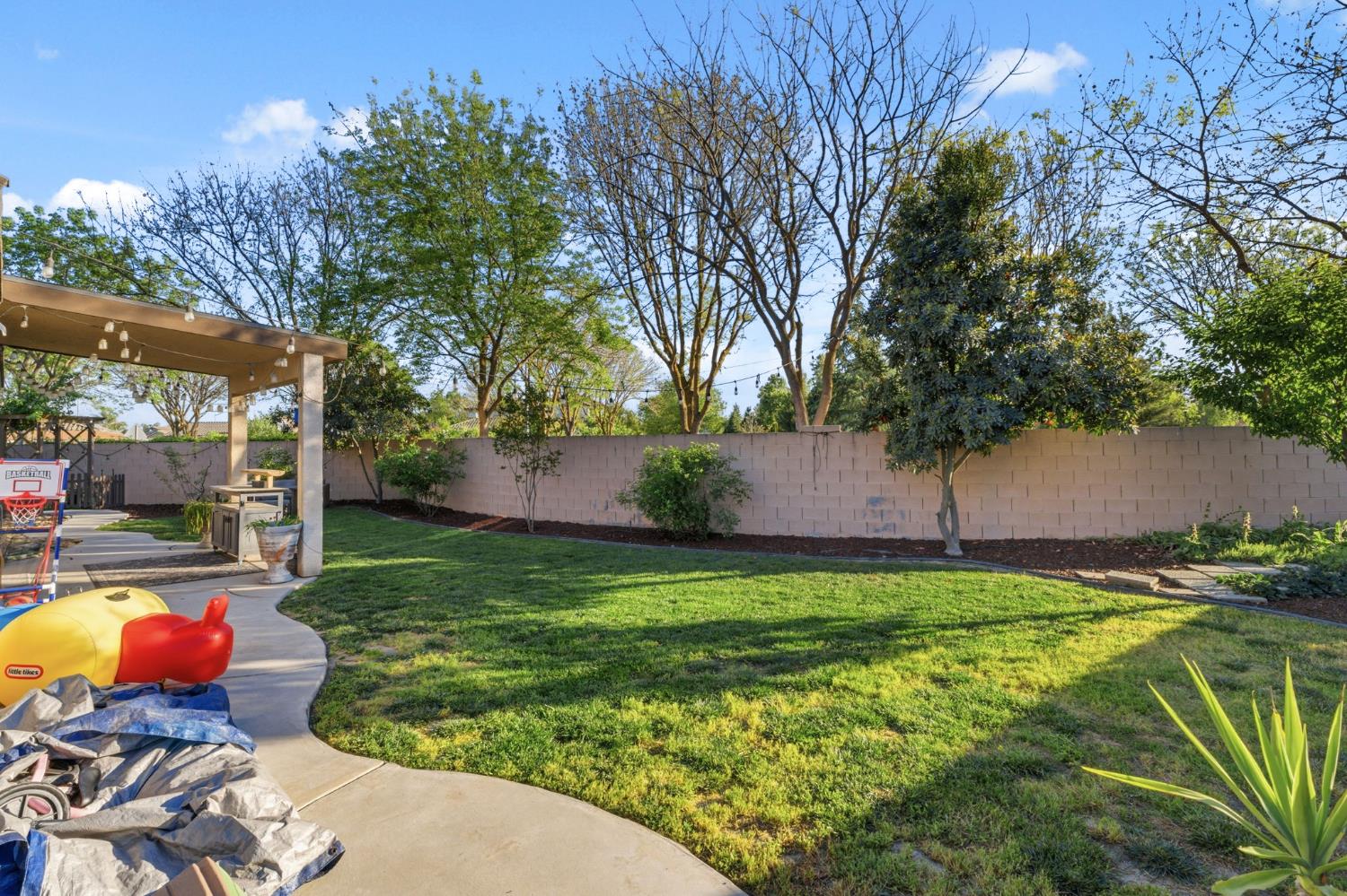 15717 West Botelho Avenue Kerman, CA 93630 - Photo 28 of 43 a backyard of a house with table and chairs and a large tree