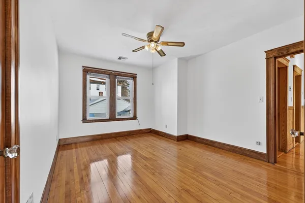 a view of empty room with wooden floor and fan