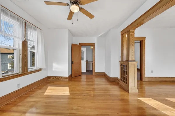 a view of an empty room with wooden floor and a window