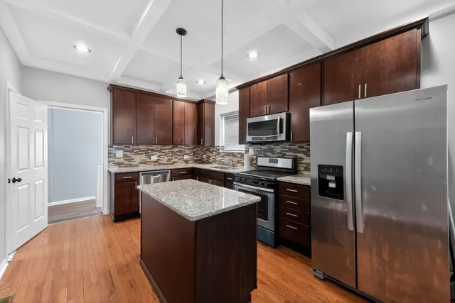 a kitchen with kitchen island granite countertop stainless steel appliances cabinets a sink and a center island